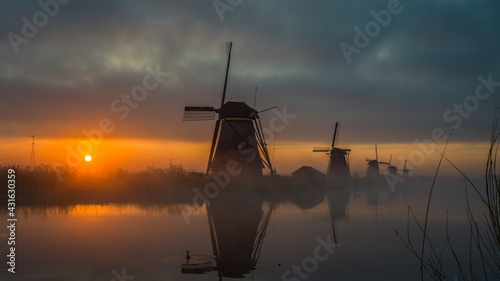 Traditionelle Windmühlen bei Sonnenaufgang im Nebel, Kinderdijk in Holland