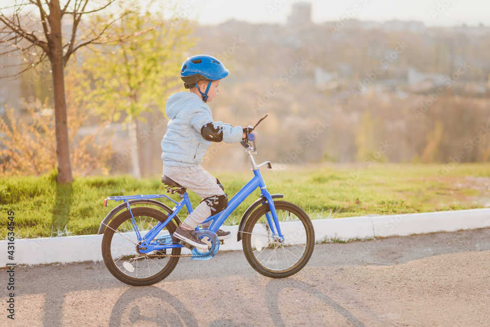 Fototapeta premium Little kid in helmet rides a bicycle on a sunny day