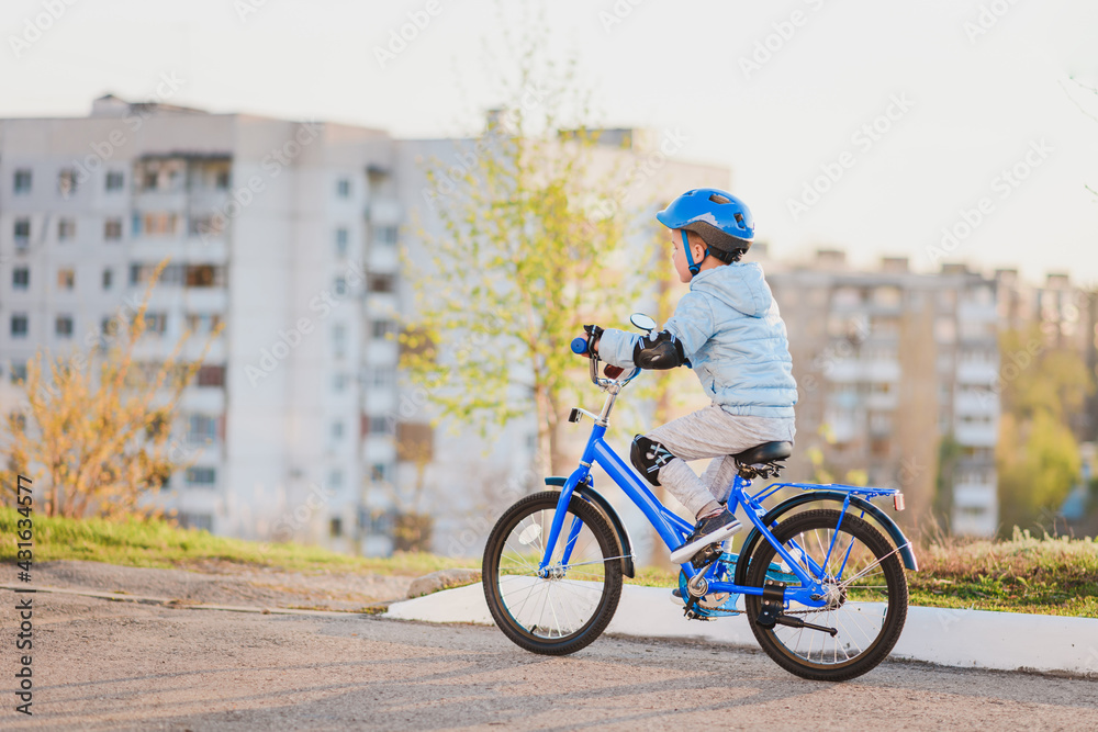 Little kid in helmet rides a bicycle on a sunny day