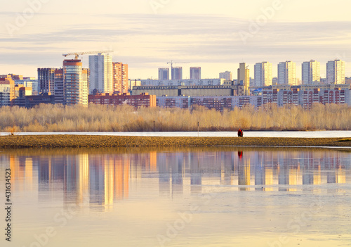 Morning on the Ob River in Novosibirsk. The high-rise buildings of the new residential area stand on the shore in the morning golden light, reflected in the water. Siberia, Russia