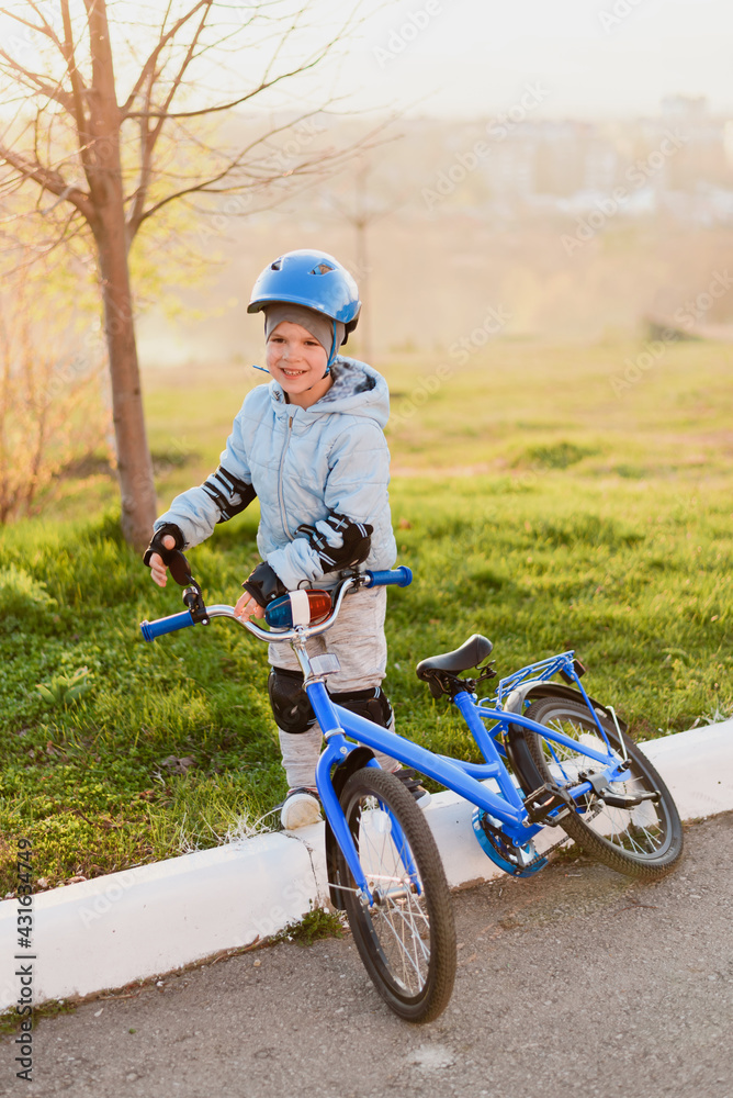 A child in a helmet learns to ride a bike on a sunny day at sunset A child in a helmet learns to ride a bike on a sunny day at sunset
