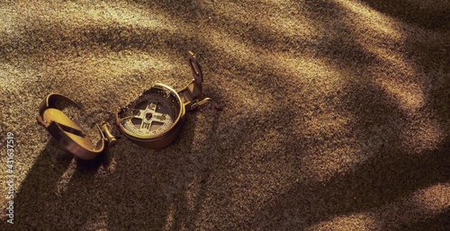Compass laying open on rippling golden sand