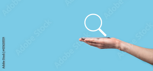 Male hand holding magnifying glass ,search icon on blue background. Concept search engine optimization, customer support.Browsing Internet Data Information.Networking Concept.