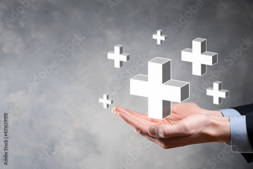 Businessman hold 3D plus icon, man hold in hand offer positive thing such as profit, benefits, development, CSR represented by plus sign.The hand shows the plus sign