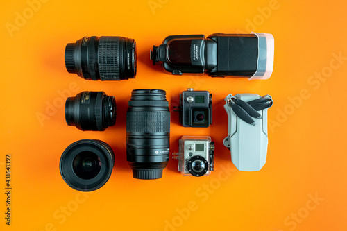 a selection of DSLR camera lenses with flash along with travel action cameras and a drone 