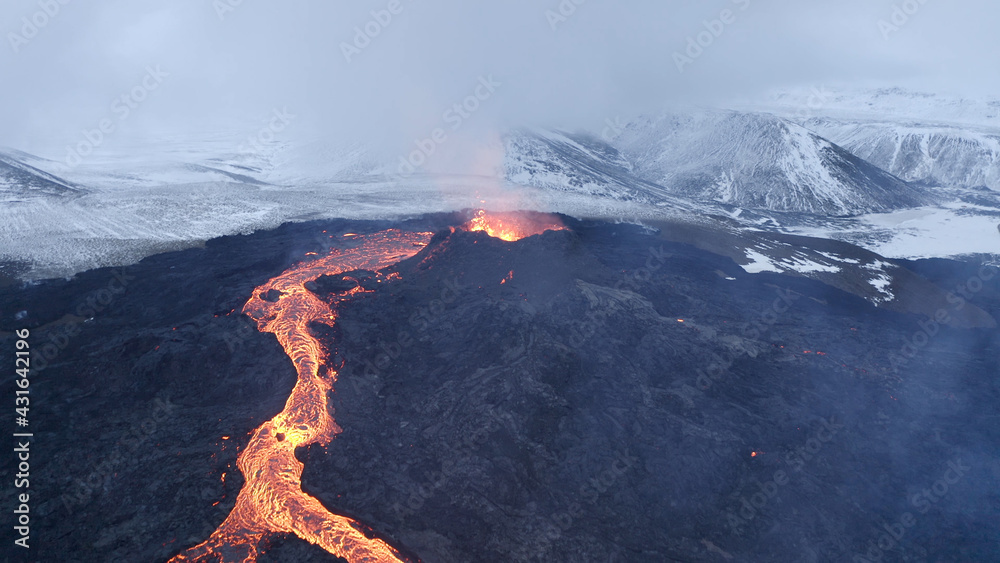 Fototapeta premium lava eruption volcano with snowy mountains, Aerial view Hot lava and magma coming out of the crater, April 2021 