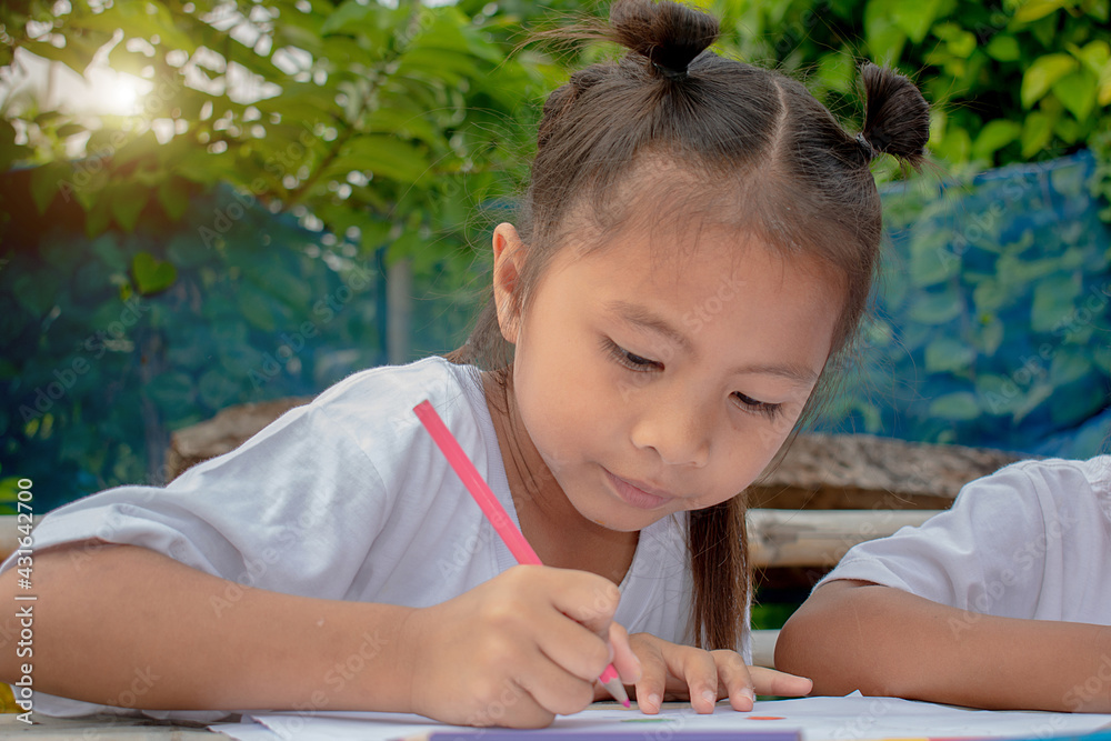 Cute cheerful child drawing using a pencil drawingwhile sitting at the table,Girl drawing and learning with educator Cute cheerful child drawing using a pencil drawingwhile sitting at the table,Girl drawing and learning with educator