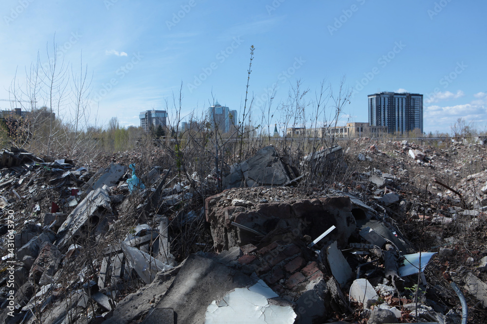 A pile of rubble of a destroyed building on the background of new buildings. Construction debris in the city.The concept of environmental pollution.A copy of the space.Photos without people.