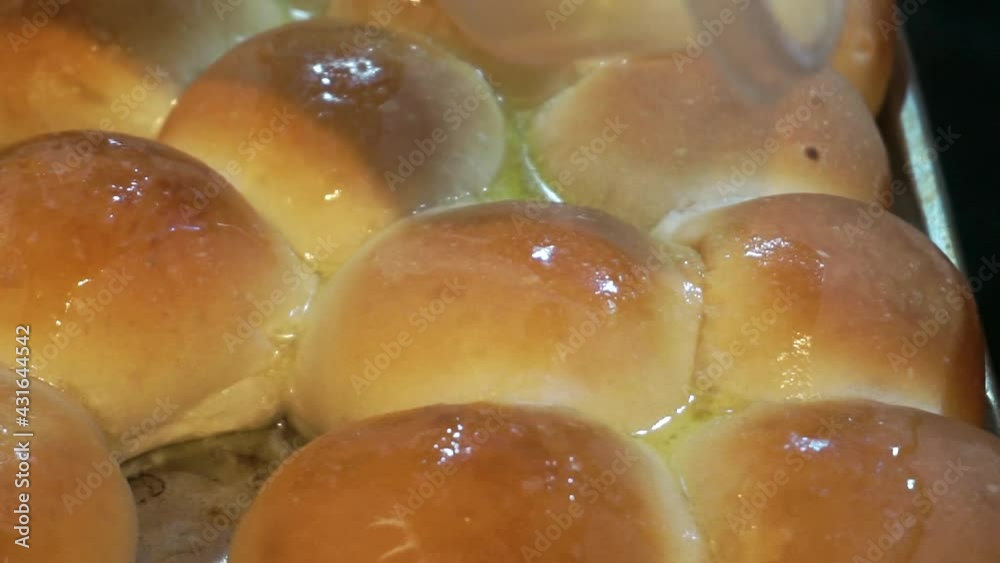 Closeup of black woman Pouring melted homemade butter over homemade dinner rolls