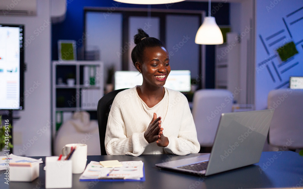 Happy african smiling because of positive results working lat at night in business office. Enthusiastic winner employee using modern technology celebrate online win success reading great data. Happy african smiling because of positive results working lat at night in business office. Enthusiastic winner employee using modern technology celebrate online win success reading great data.