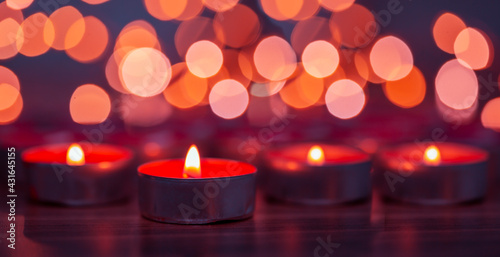 red candles burning in front of a bokeh background