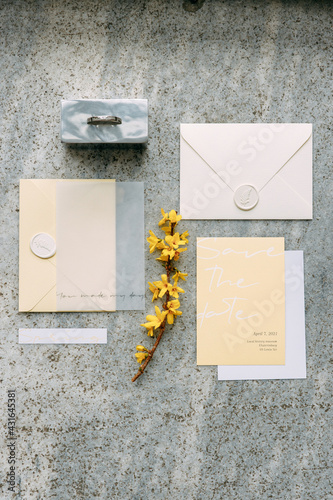 Stylish wedding invitations on a gray stone background. Wedding printing set in trendy yellow shades, envelope and cards.
