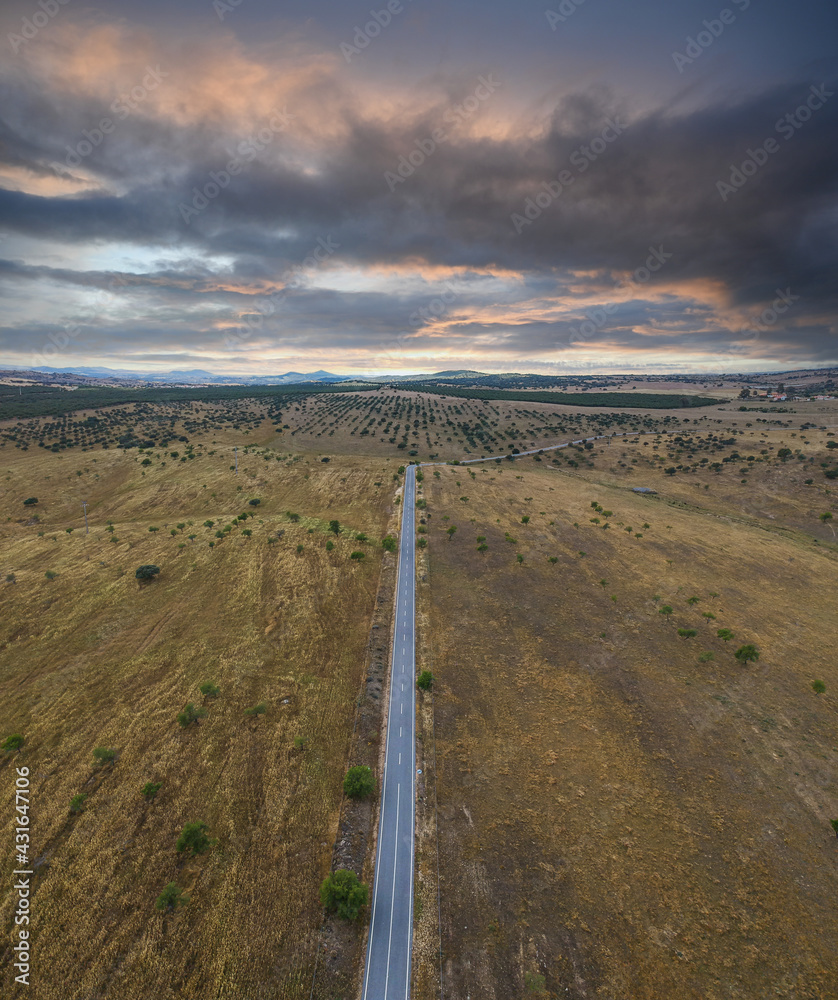Aerial view of a country road in spring with stormy clouds in background