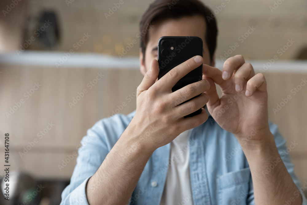 Close up cropped of man using smartphone, browsing mobile device apps, typing and looking on screen, scrolling, young male chatting in social networks or shopping online, holding phone in hands