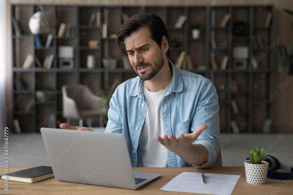 Unhappy dissatisfied businessman looking at laptop screen, reading bad news in message, frustrated stressed young man having problem with broken or discharged device, data loss or software failure