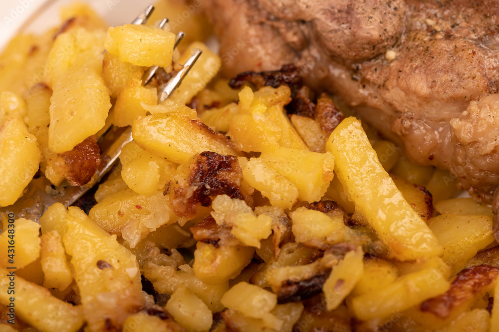 Homemade fried potatoes and a large piece of meat on a white plate. Homemade fried potatoes and a large piece of meat on a white plate.