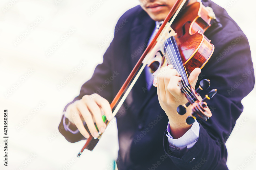 Fototapeta premium A musician man is practicing the violin playing with the melodiousness on bright background. Selected focus.