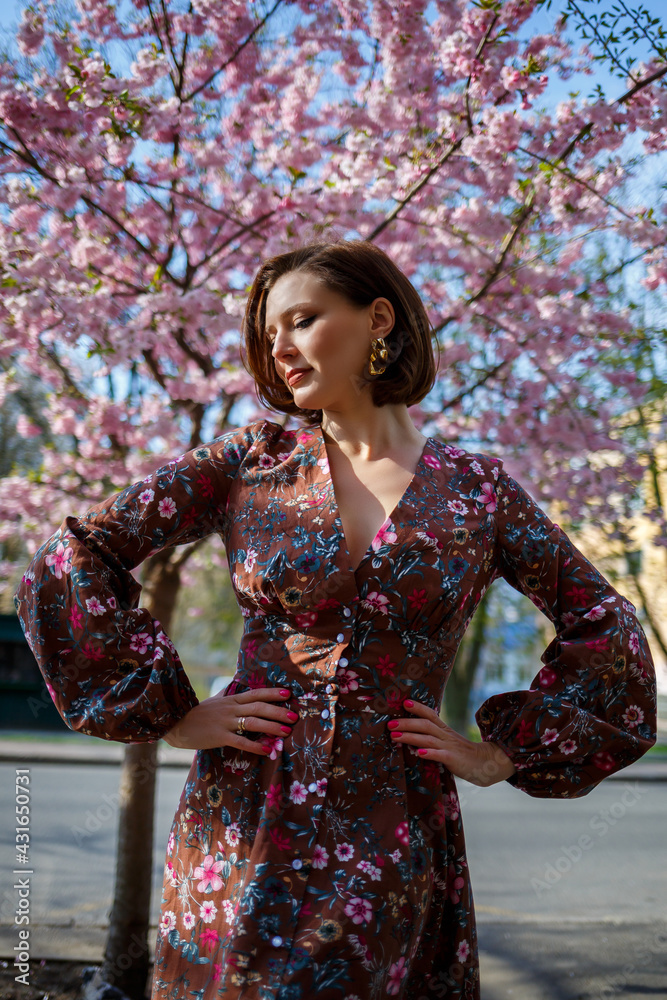 Portrait of a cute and beautiful woman girl in a dress in the garden in the middle of blooming sakura. spring and sun time. Blurred background and selected focus. Portrait of a cute and beautiful woman girl in a dress in the garden in the middle of blooming sakura. spring and sun time. Blurred background and selected focus.