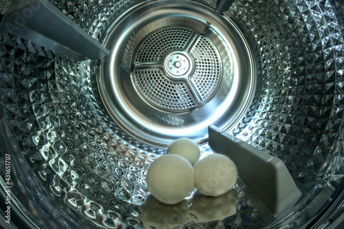 The look inside the shiny metal drum of the modern dryer with three  balls which help to dry the clothing faster. 