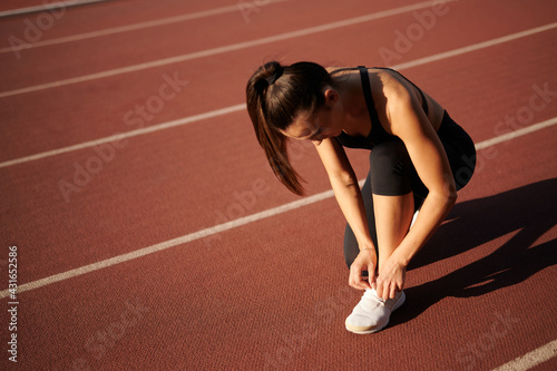 sportswoman in the stadium laces up her laces © Vita