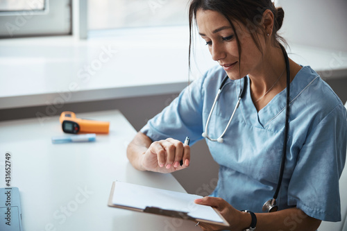 Charming female doctor doing paperwork in clinic