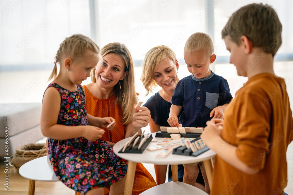 Lesbian couple at the table playing board game with children.