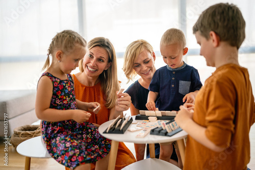 Lesbian couple at the table playing board game with children.