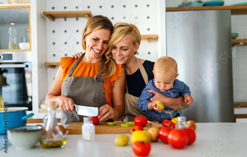 Portrait of female couple in the kitchen with their daughter