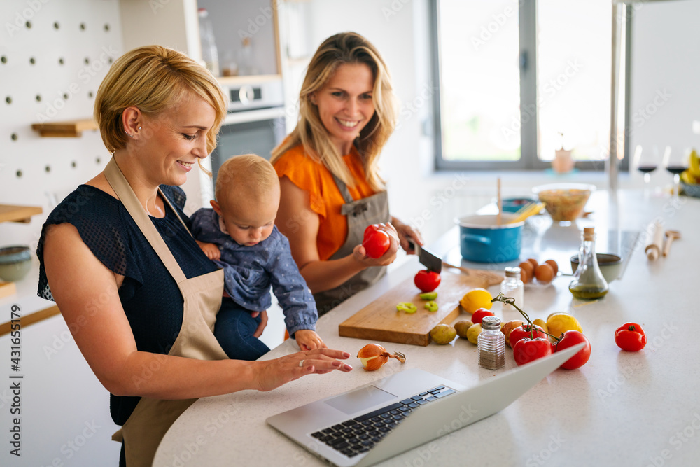 Fototapeta premium Happy women preparing healthy food and having fun with kid in kitchen.