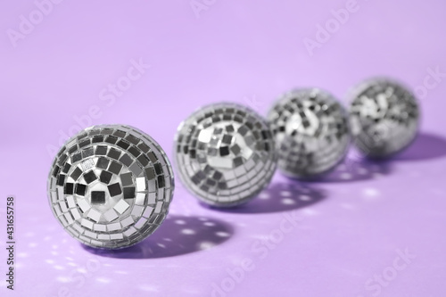 Row of shiny disco balls on lilac background