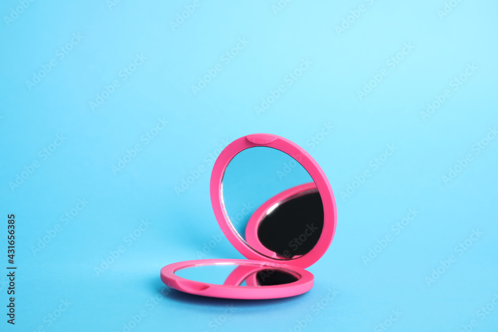 Stylish cosmetic pocket mirror on light blue background Stylish cosmetic pocket mirror on light blue background