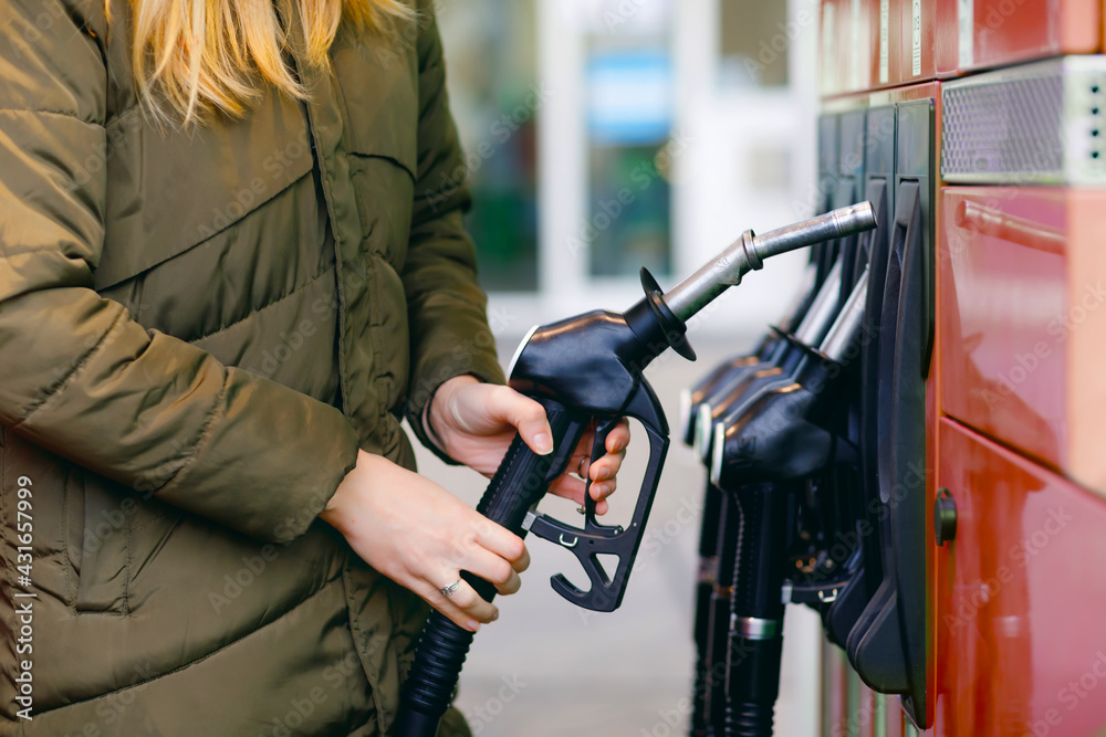 Close-up of hands of woman at self-service gas station, hold fuel nozzle and refuel the car with petrol, diesel, gas. Close up of filling auto with gasoline or benzine. Self service gas pump Close-up of hands of woman at self-service gas station, hold fuel nozzle and refuel the car with petrol, diesel, gas. Close up of filling auto with gasoline or benzine. Self service gas pump