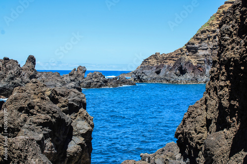 Grandes montañas de rocas en las costas del mar con un cielo azul y nubes blancas  photo