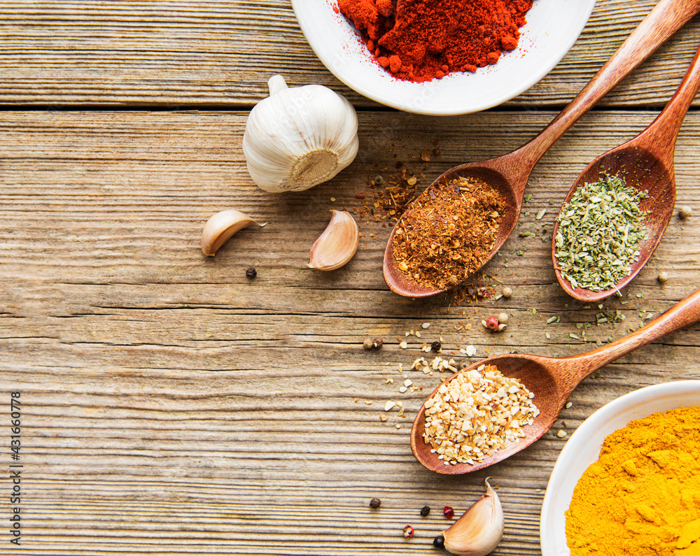 A selection of various colorful spices on a wooden table in bowls and spoons A selection of various colorful spices on a wooden table in bowls and spoons