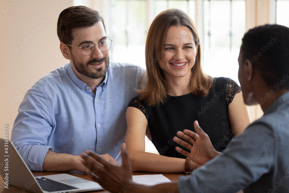 Happy young caucasian family couple visiting african american professional lawyer, broker or financial advisor at office, discussing services or contract agreement, feeling satisfied with consultation