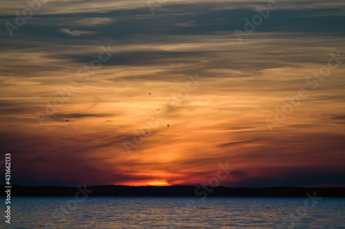 Krajobraz zachód słońca nad wodą z pięknie oświetlonym niebem © Monika
