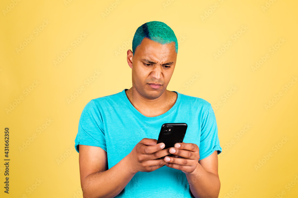Black african man in casual on yellow background with mobile phone looks with disgust, disgruntled face negative emotions