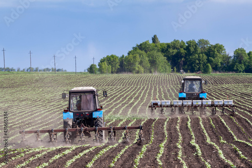 field work in agriculture. farmer's tractor harrows the field after planting seeds. tractor and seeder planting crops on a field.