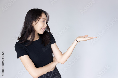 Happy, smiling, confident asian young adult woman pointing to blank space