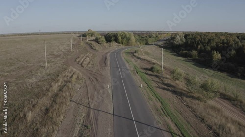 The quadcopter flies over the road and the forest
