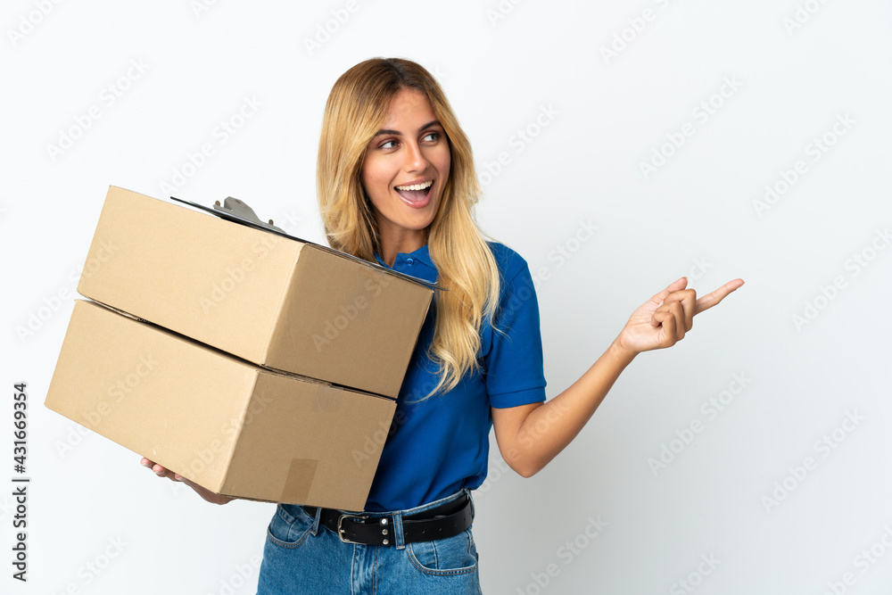Young blonde Uruguayan delivery woman isolated on white background pointing finger to the side and presenting a product Young blonde Uruguayan delivery woman isolated on white background pointing finger to the side and presenting a product