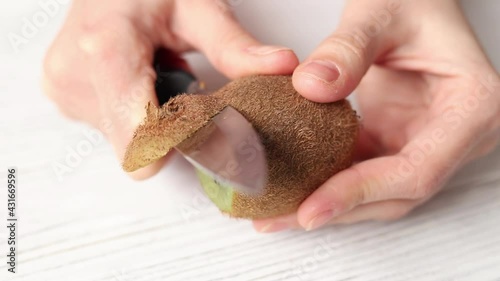  Woman cuts ripe kiwi fruit, close-up