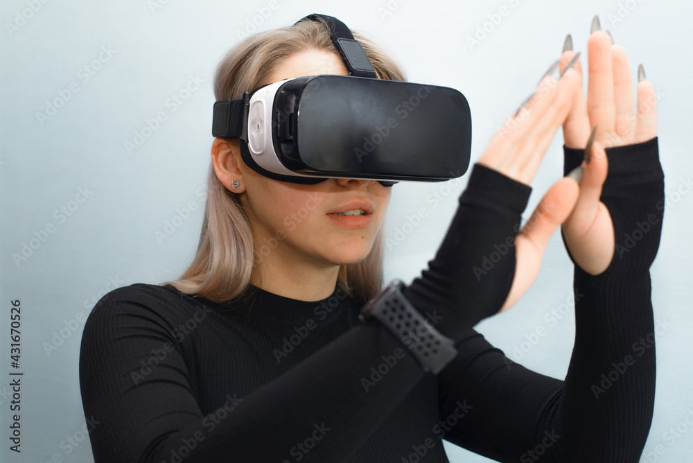 Young woman in VR glasses touching virtual reality with her hands. Girl using interactive device, indoors. New technologies, simulation equipment, helmet 3D concept. Focus on the face Young woman in VR glasses touching virtual reality with her hands. Girl using interactive device, indoors. New technologies, simulation equipment, helmet 3D concept. Focus on the face