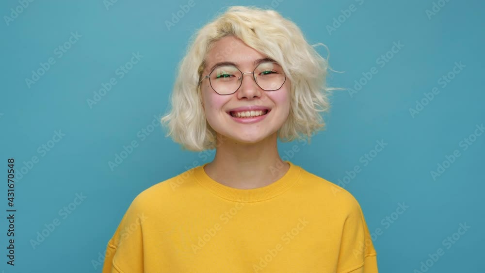 Attractive asian young woman face close up turns her head to camera glasses with smile with white curly hair yellow clothes on blue background Portrait Teen girl feel happy Positive emotions Lifestyle Attractive asian young woman face close up turns her head to camera glasses with smile with white curly hair yellow clothes on blue background Portrait Teen girl feel happy Positive emotions Lifestyle