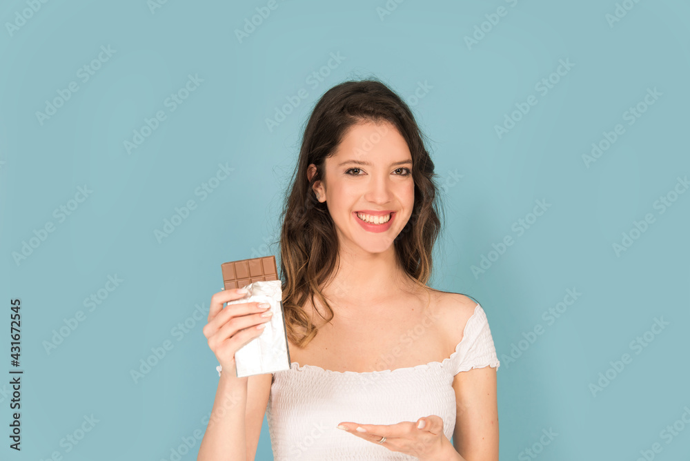 Caucasian woman with chocolate bar smiling isolated on blue background Caucasian woman with chocolate bar smiling isolated on blue background