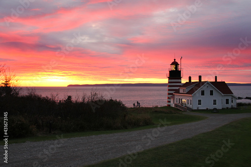 Sunrise accents the red and white striped West Quoddy Head Lighthouse in Lubec Maine. photo