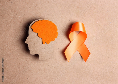 Bild auf Leinwand Orange awareness ribbon and brain symbol on a brown background.
