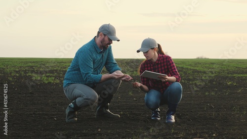 Business man and an agronomist are studying seedlings of crops in field. Business people teamwork. Farmers man, woman work in field with computer tablet. Smart farming technologies in agriculture photo