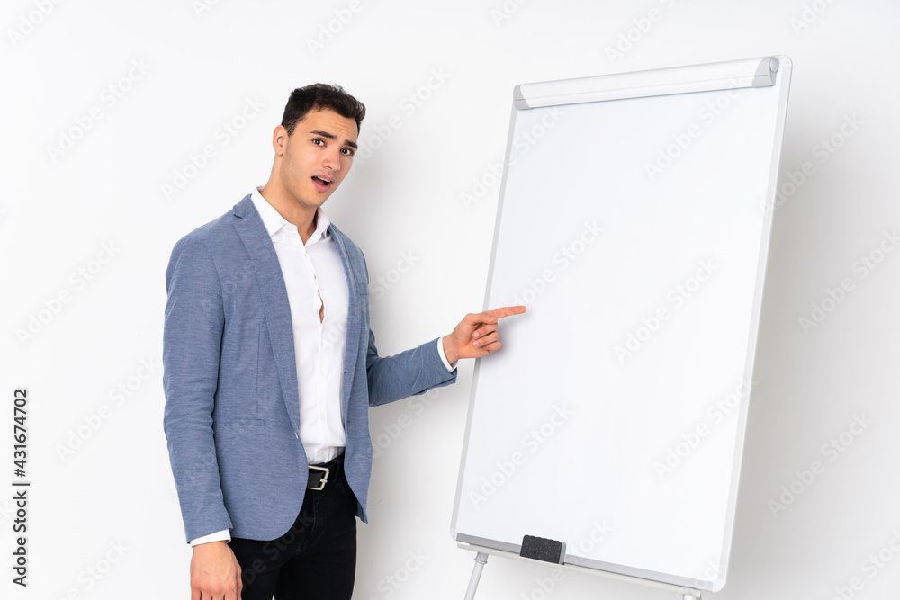 Young caucasian handsome man isolated on purple background giving a presentation on white board Young caucasian handsome man isolated on purple background giving a presentation on white board