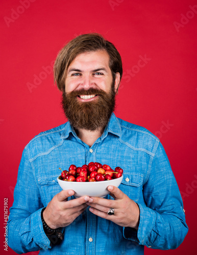 happy bearded man holding cherry. summer harvest. fruit full of vitamins. healthy food and eating. dieting concept. mature brutal hipster with red berry bowl. natural and organic